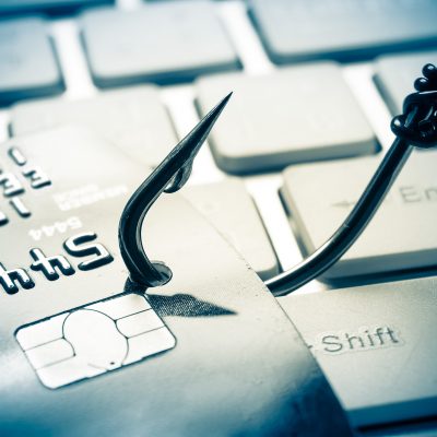 credit card phishing - piles of credit cards with a fish hook on computer keyboard